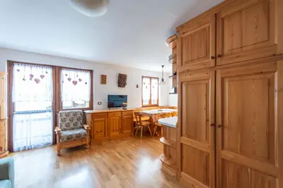 a kitchen with wooden cabinets and a dining room at Casa Piz Meda in Soraga