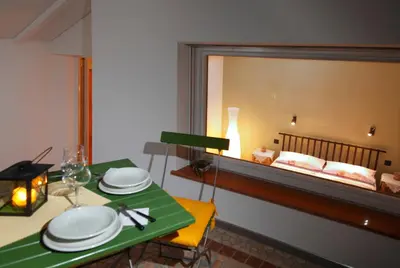 a dining room with a table and a bed in the window at viaDolceVita - Blaue Gästewohnung in Lana