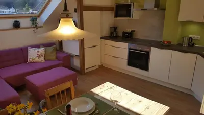a small kitchen and living room with a purple couch at viaDolceVita - Grüne Gästewohnung in Lana
