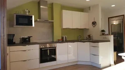 a kitchen with white cabinets and a tv on the wall at viaDolceVita - Grüne Gästewohnung in Lana