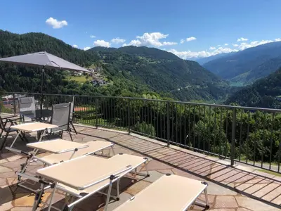 a balcony with tables and chairs and mountains at B and B nonna Rosa vista Lagorai in Capriana
