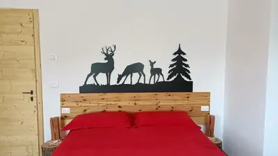 a bedroom with a bed with red sheets and deer decals at Casa Alpina in Cavalese