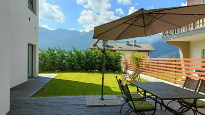 a patio with a table and chairs and an umbrella at Casa Alpina in Cavalese