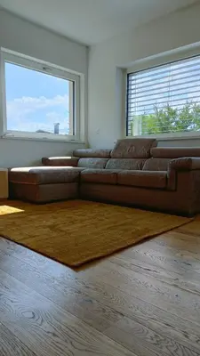 a brown couch in a living room with a large window at Casa Alpina in Cavalese