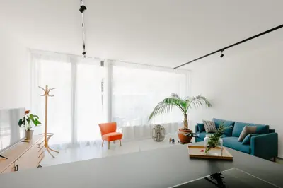 a living room with a blue couch and orange chair at La Villetta 17 - smarter Rückzugsort für die großen Winter-Wettkämpfe in Lana