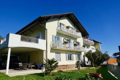 a large white building with two balconies and a yard at Strengen Guesthouse in Caldaro