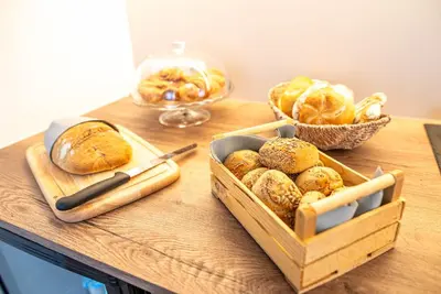 a table with two trays of bread and a basket of pastries at Strengen Guesthouse in Caldaro