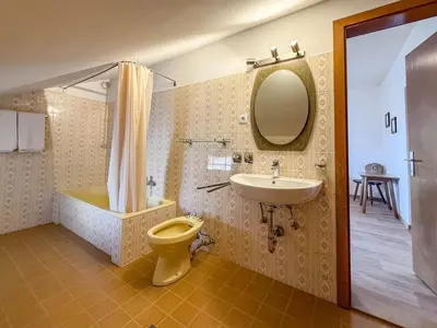 a bathroom with a sink and a toilet and a mirror at Strengen Guesthouse in Caldaro