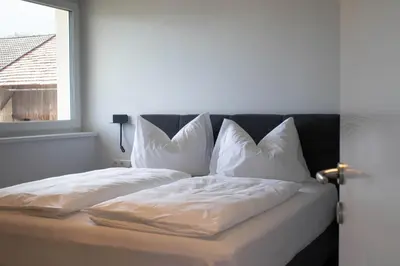 a bed with white sheets and pillows next to a window at CasaLuNa in Appiano sulla Strada del Vino