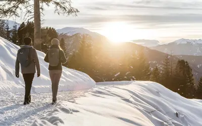 two people walking down a snow covered path in the mountains at View House - Chalet Goyen in Schenna