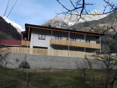 a house with a fence and mountains in the background at Fewo Windbichl in Parcines
