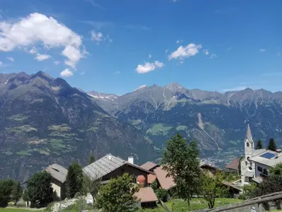 a village with a church and mountains in the background at Fewo Windbichl in Parcines