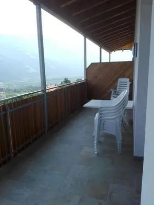 a balcony with white chairs and a table with a view at Fewo Windbichl in Parcines