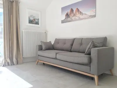 a gray couch in a living room with a window at Emma Suite Merano in Merano