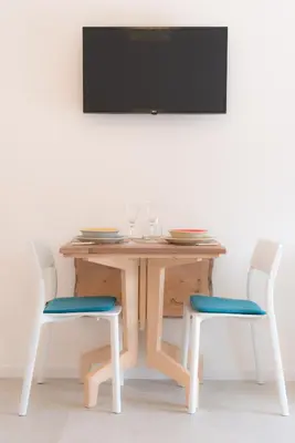 a table with two chairs and a television on a wall at Emma Suite Merano in Merano