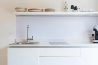 a kitchen with white cabinets and a sink at Emma Suite Merano in Merano