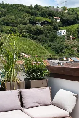 a couch sitting on top of a balcony with plants at Emma Suite Merano in Merano