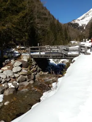 a bridge over a river in the snow at Appartamento Riscone Nuvola di Plan in Brunico