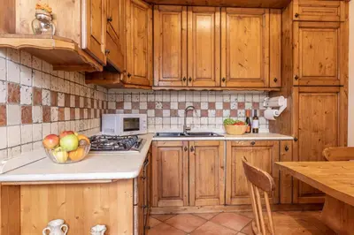 a kitchen with wooden cabinets and a bowl of fruit on the counter at Casa Cristallo in Cortina dʼAmpezzo