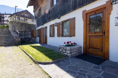 a house with a wooden door and flowers in a yard at Casa Cristallo in Cortina dʼAmpezzo