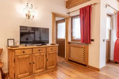 a living room with a television on a wooden dresser at Casa Cristallo in Cortina dʼAmpezzo
