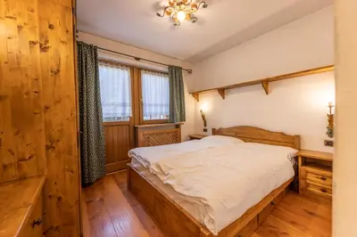 a bedroom with a bed and a chandelier at Casa Cristallo in Cortina dʼAmpezzo