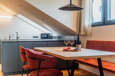 a table with two glasses of wine and some chairs at Kandlerhof in Bolzano