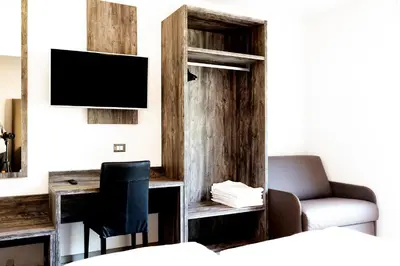 a room with a desk with a television and a chair at Roma Ariston 7 in Bolzano