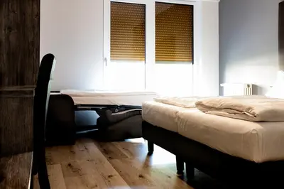 a bedroom with a bed and a table and window at Roma Ariston 7 in Bolzano