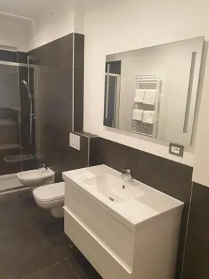 a bathroom with a sink and a toilet and a mirror at Roma Ariston 7 in Bolzano