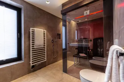 a bathroom with a glass shower and a toilet at Villa Margareth in Selva di Val Gardena
