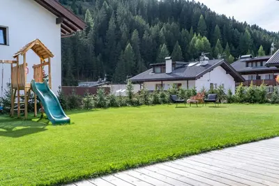a yard with a playground with a slide at Villa Margareth in Selva di Val Gardena