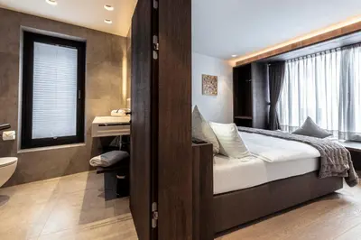 a bedroom with a bed and a bathroom with a window at Villa Margareth in Selva di Val Gardena