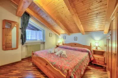 a bedroom with a large bed and a wooden ceiling at CASA CAVALESE in Cavalese