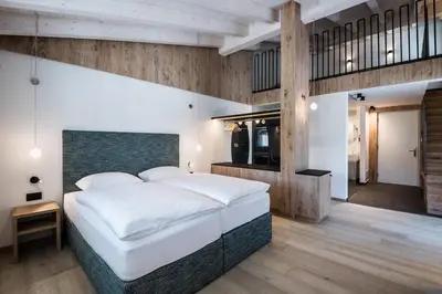 a bedroom with a large white bed and wooden walls at Hotel Ciasa Tamá in La Villa