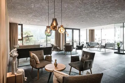 a living room with a grand piano and chairs at Hotel Ciasa Tamá in La Villa
