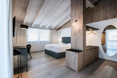 a bedroom with a bed and a desk and a mirror at Hotel Ciasa Tamá in La Villa