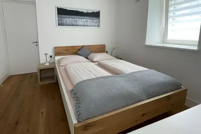 a bed in a bedroom with a wooden frame at Apartments Griesser - Included BrixenCard and parking garage in house in Bressanone