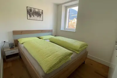 a bedroom with a bed with yellow sheets and a window at Apartments Griesser - Included BrixenCard and parking garage in house in Bressanone