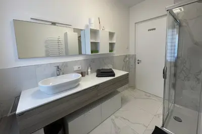 a white bathroom with a sink and a shower at Apartments Griesser - Included BrixenCard and parking garage in house in Bressanone