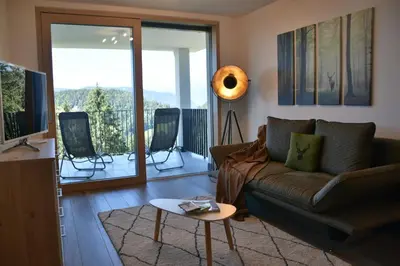 a living room with a brown couch and a balcony at Panoramaresidence Hafling in Avelengo