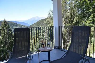 a balcony with two chairs and a table and mountains at Panoramaresidence Hafling in Avelengo