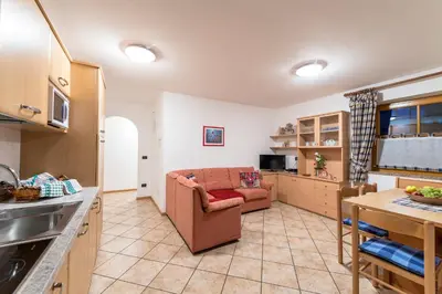 a kitchen and living room with a couch and a table at Cèsa Bel Seren in Campitello di Fassa