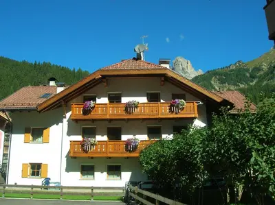 a building with a balcony with flowers on it at Cèsa Bel Seren in Campitello di Fassa