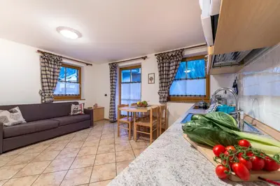 a kitchen and living room with a couch and a table at Cèsa Bel Seren in Campitello di Fassa