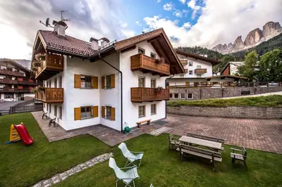 a house with a yard with a table and chairs at Cèsa Bel Seren in Campitello di Fassa