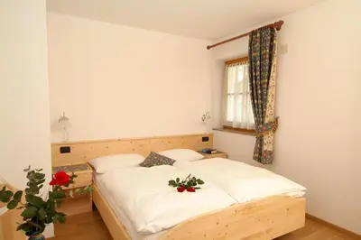 a bedroom with a bed and a window at Cèsa Bel Seren in Campitello di Fassa