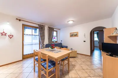 a kitchen and living room with a table and chairs at Cèsa Bel Seren in Campitello di Fassa