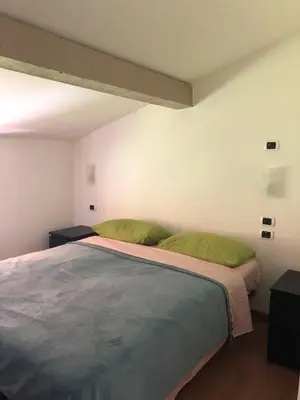 a bedroom with a large bed with two green pillows at Appartamento Primiero San Martino di Castrozza in Fiera di Primiero