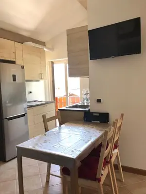 a kitchen with a table with chairs and a refrigerator at Appartamento Primiero San Martino di Castrozza in Fiera di Primiero